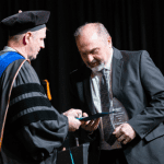 Dr. Meeker receiving lifetime achievement award, man receiving award on stage