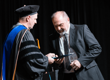 Dr. Meeker receiving lifetime achievement award, man receiving award on stage